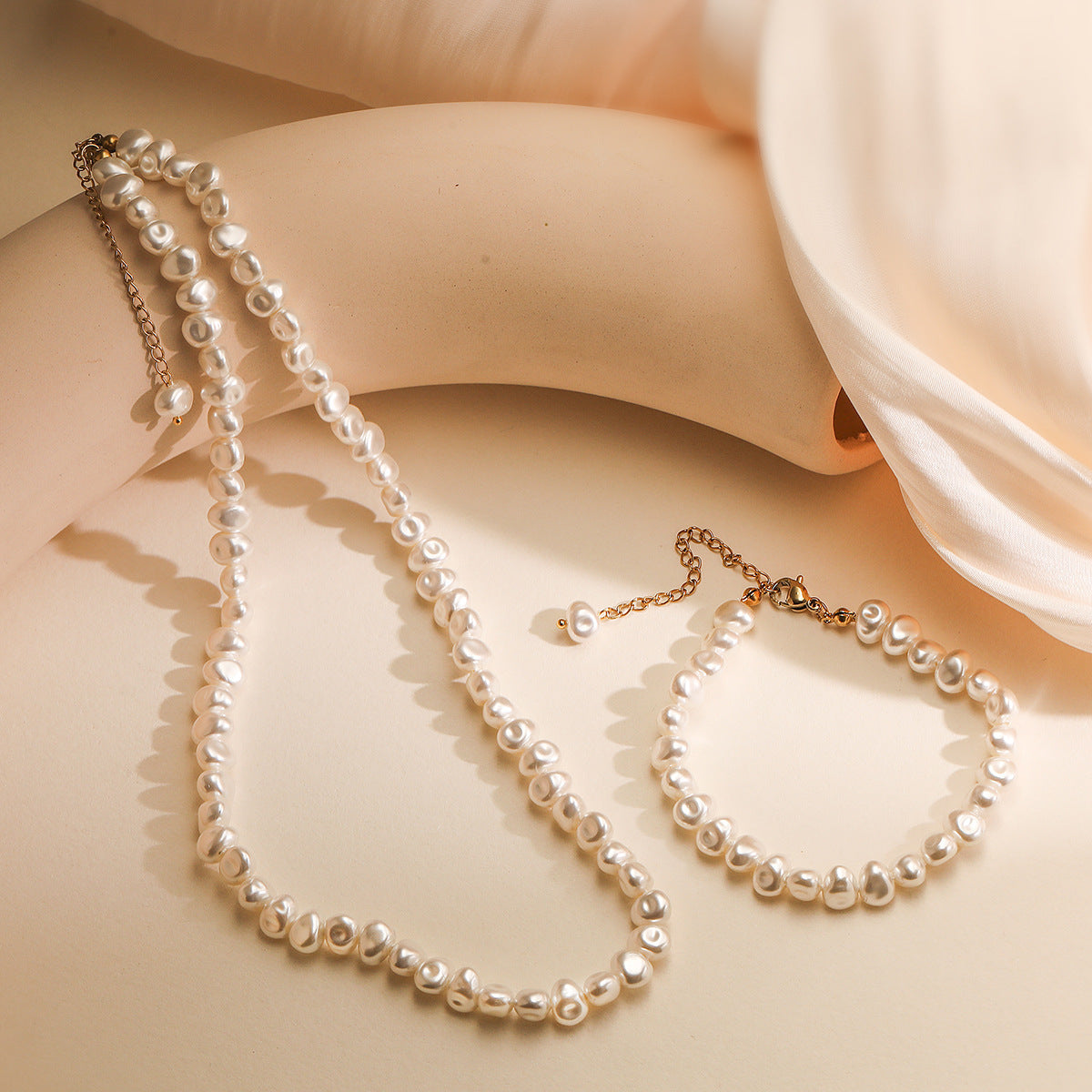 Pearl necklace and earrings on a soft fabric background